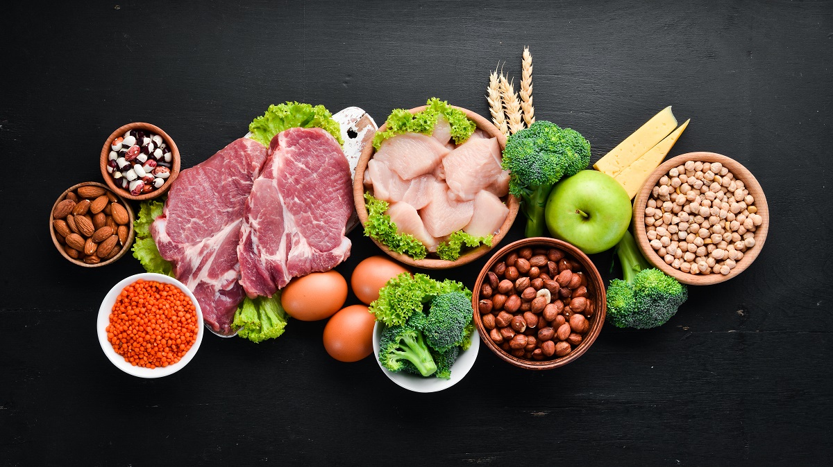 Omasă neagră pe care se află alimente bogate în proteine cum ar fi carnea, lintea, broccoli, mere, pentru a ilustra câteav semne care indică un consum prea mare de proteine