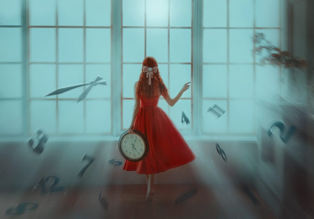 Fată cu rochie lungă roșie stă cu fața către geam și privește spre soare pe un fundal albastru deschis cu alb