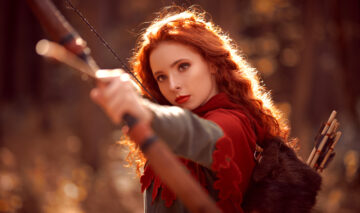 Fată frumoasă cu părul roșcat ține un arc cu săgeți în mână