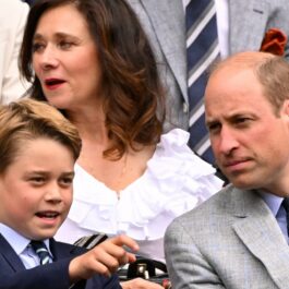 Prințul George, într-un costum închis la culoare, alături de tatăl său, în tribune la Wimbledon