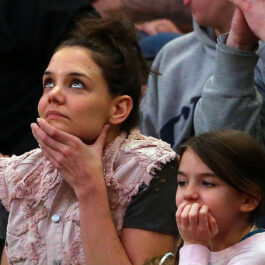 Suri Cruise, alături de mama ei, Katie Holmes, în tribuna unui eveniment sportiv, în timp ce se uită spre tabela de marcaj