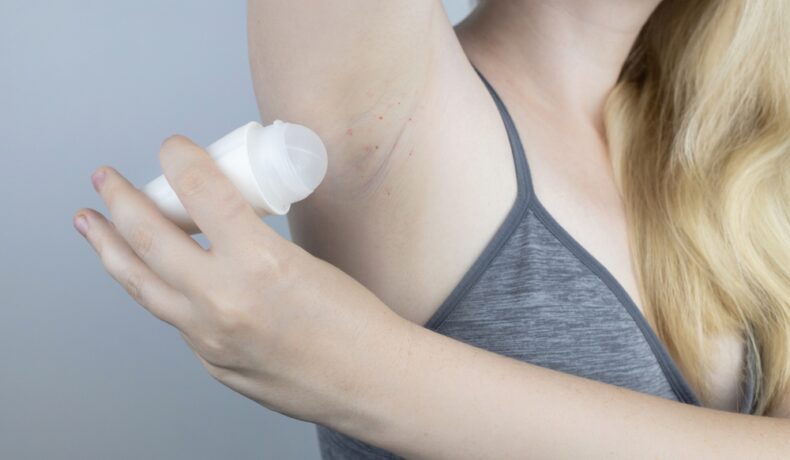 O femeie care se dă cu deodorant și are axila iritată
