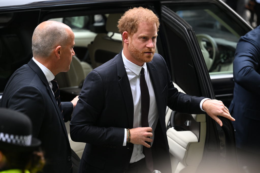 Prințul Harry, fotografiat în timp ce coboară din mașină, ajutat de un agent de securitate