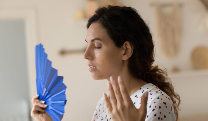 O femei care se confruntă cu bufeuri în timpul apariției menopauzei