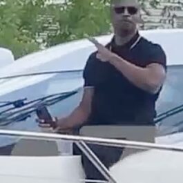 Jamie Foxx într-un tricou negru, pe o barcă, în timp ce își salută fanii
