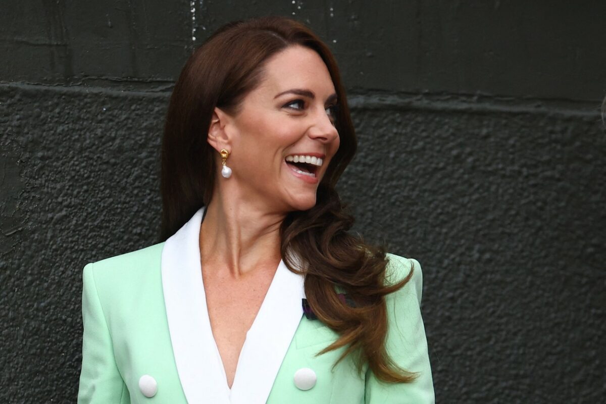 Kate Middleton, zâmbitoare, în timp ce se pregăteste să urmărească un eveniment pe terenul de tenis
