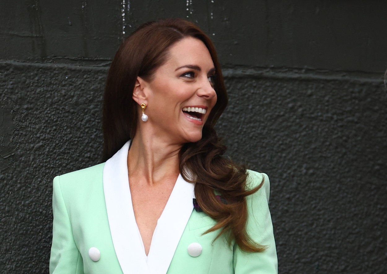 Kate Middleton, zâmbitoare, în timp ce se pregăteste să urmărească un eveniment pe terenul de tenis