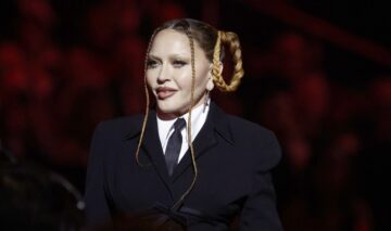Madonna într-un costum negru și cu părul prins în cozi în timpul unui eveniment public