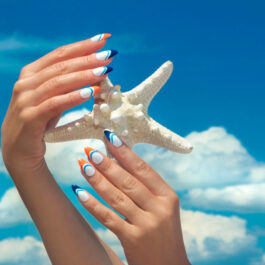 O femeie cu unghii cu model marin care ține o stea de mare în mâini