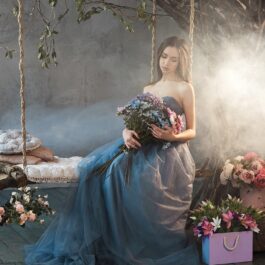 O femeie frumoasă care stă pe un leagăn cu flori pentru a ilustra una dintre zodiile care va avea inima frântă în 2023