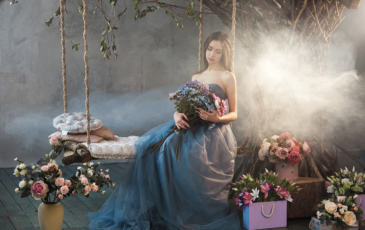 O femeie frumoasă care stă pe un leagăn cu flori pentru a ilustra una dintre zodiile care va avea inima frântă în 2023