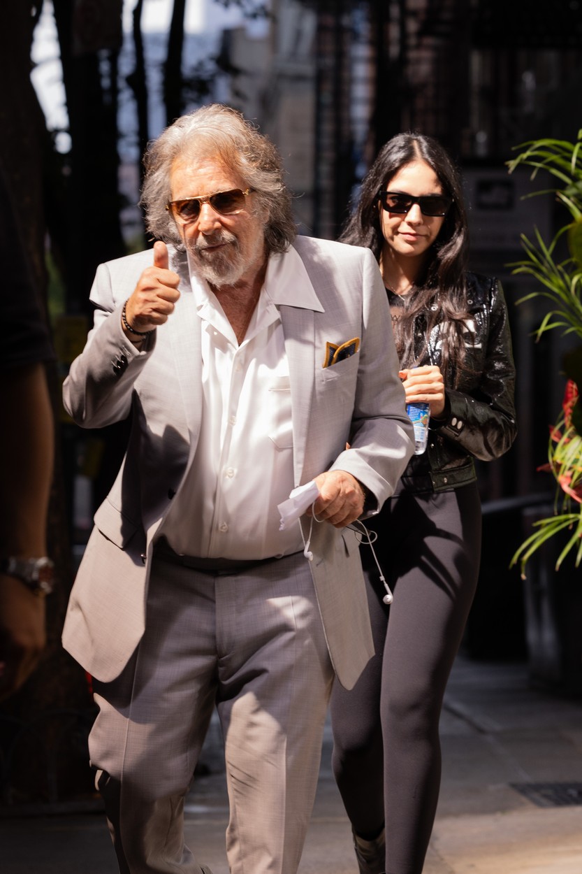 Îmbrăcat într-un costum gri, la care și-a pus cămașă albă și ochelari de soare negri, Al Pacino, merge în fața partenerei sale care poartă negru din cap până în picioare