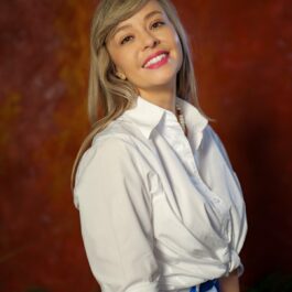 Alexandra Mircea într-o cămașă albă și o fustă colorată
