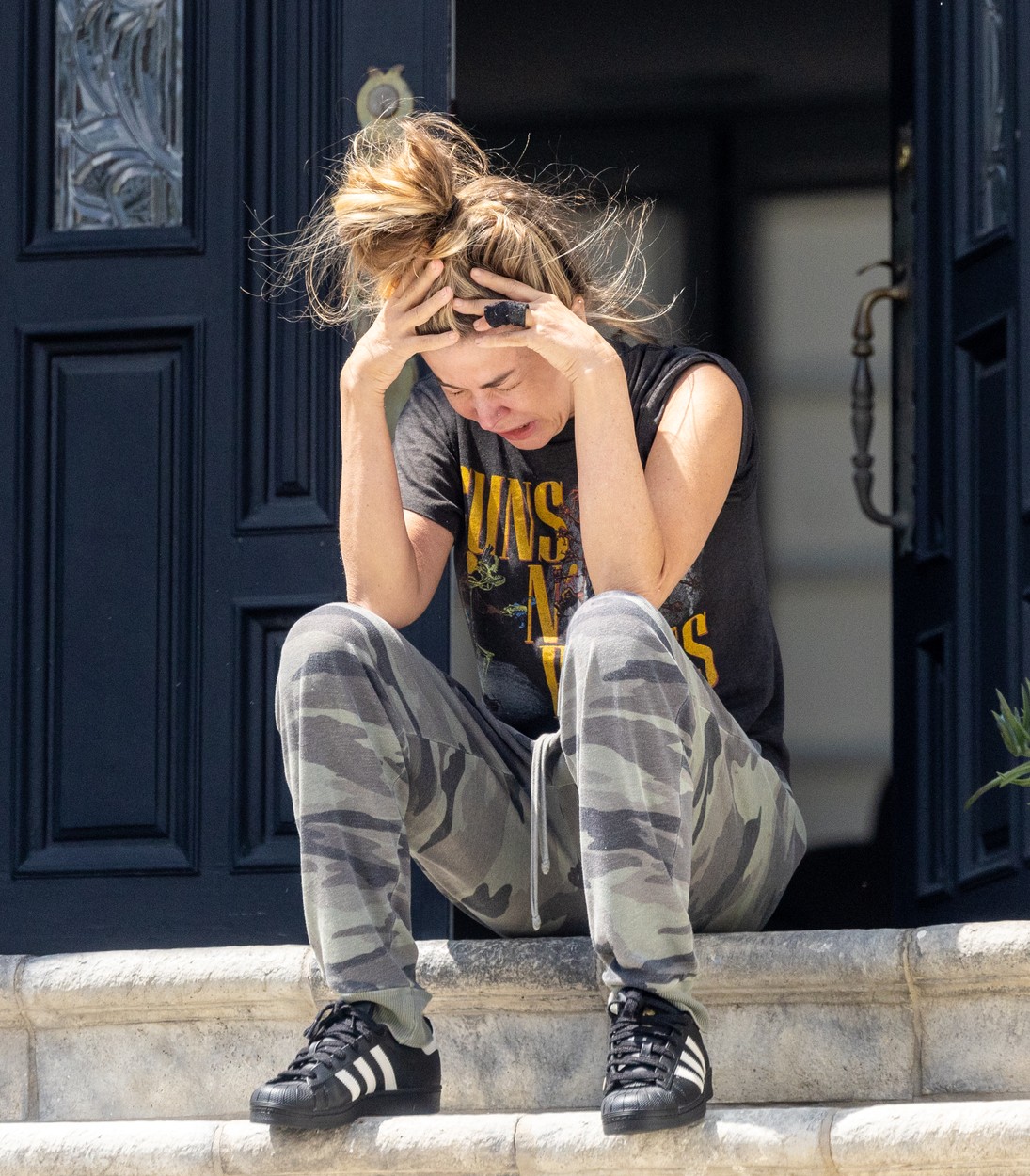 Carmen Electra este așezată pe una dintre treptele scărilor aflate în fața casei sale și este îmbrăcată cu tricou cu Guns N’ Roses, pantaloni de camuflaj, pantofi sport