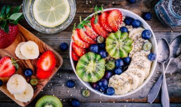 O imagine în care apare un mic dejun sănătos care cuprinde un bol cu terci de ovăz, felii de banană, kiwi, căpșune, afine și semințe de chia