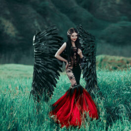 O tânără brunetă, îmbrăcată într-o rochie neagră cu roșu, croită în stilul sirenă. Ea are aripi negre de înger.