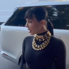 Kim Kardashian, într-o rochie neagră, cu mai multe coliere groase la gât, din aur
