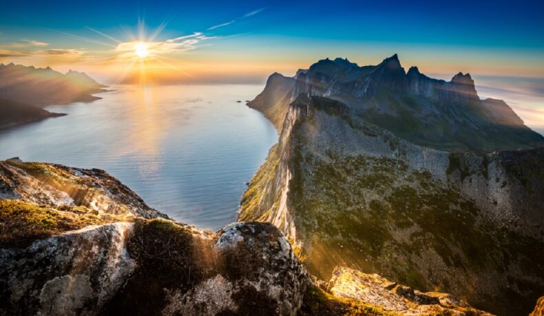 Poză realizată din vârful Segla și se văd munții, dar și Soarele care strălucește puternic pe cerul Norvegiei