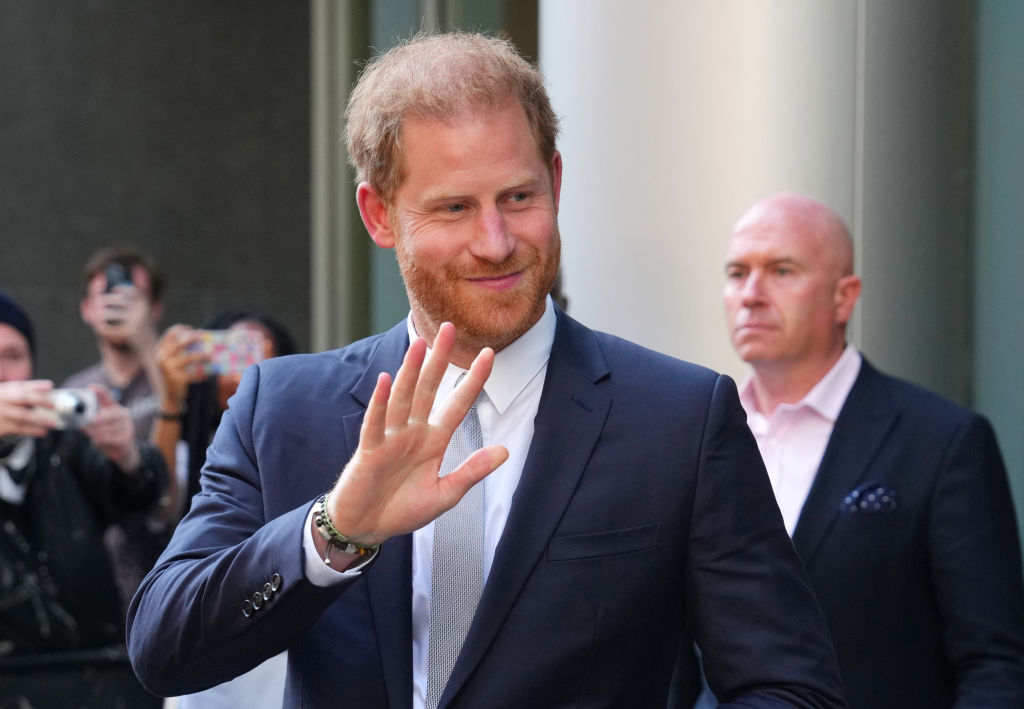 Prințul Harry, fotografiat în timp ce salută fanii, la ieșirea dintr-o clădire