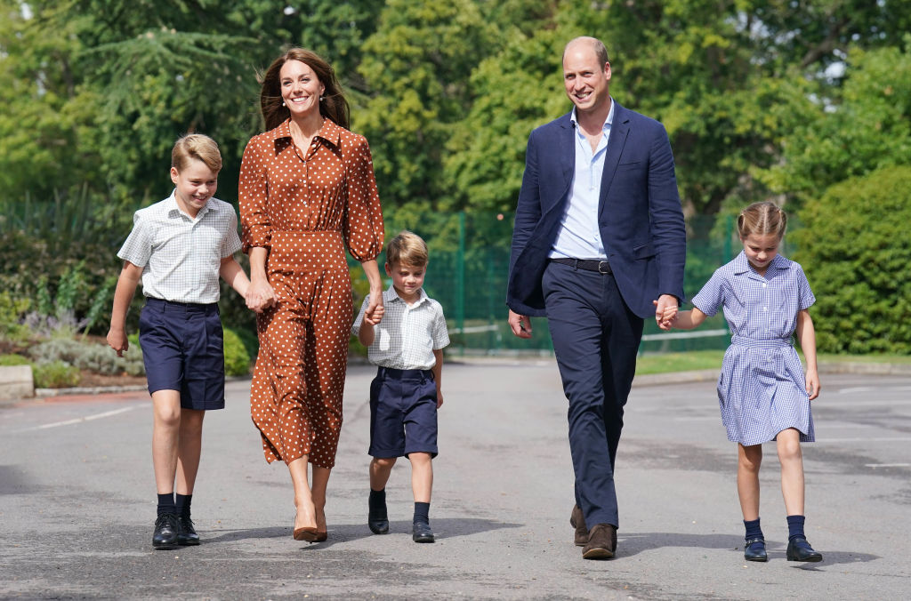 Prințul George, Prințesa Charlotte și Prințul Louis sunt de mână cu părinții lor și merg spre Școala Lambrook. Poza a fost realizată pe 7 septembrie 2022
