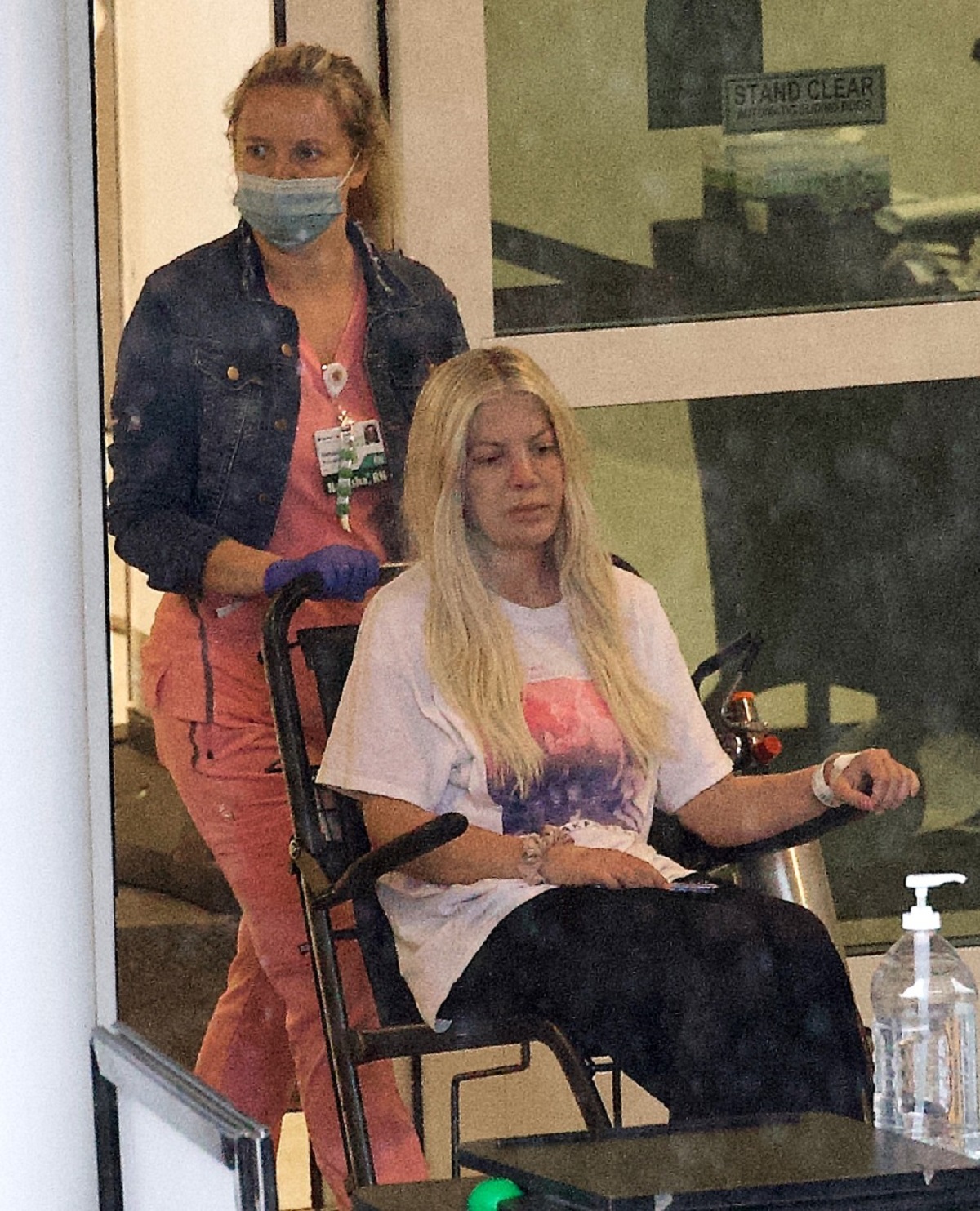 Tori Spelling în timp ce este scoasă din spital de o asistentă cu ajutorul unui cărucior cu rotile