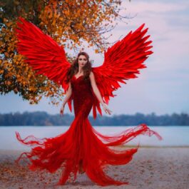 O tânără brunetă care a pozat în timp ce purta o rochie roșie impresionantă și aripi de înger