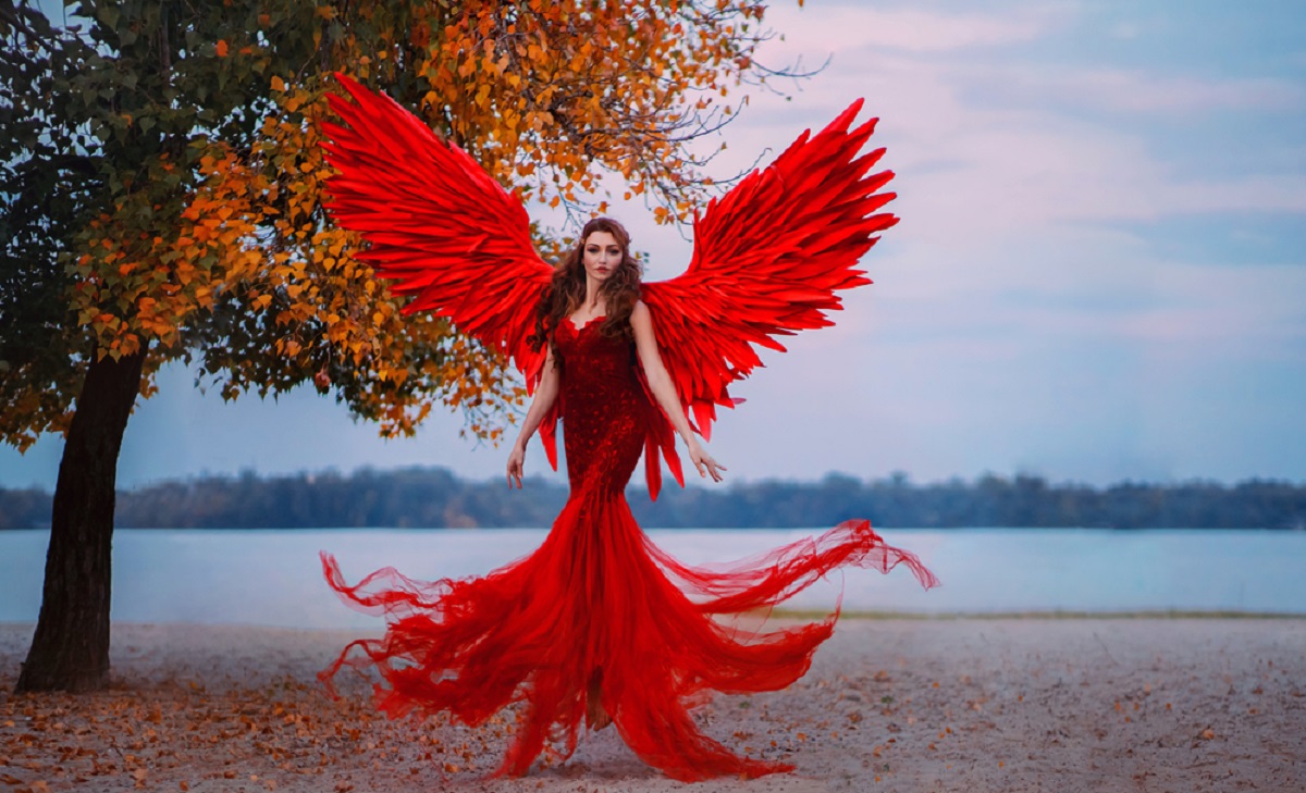 O tânără brunetă care a pozat în timp ce purta o rochie roșie impresionantă și aripi de înger
