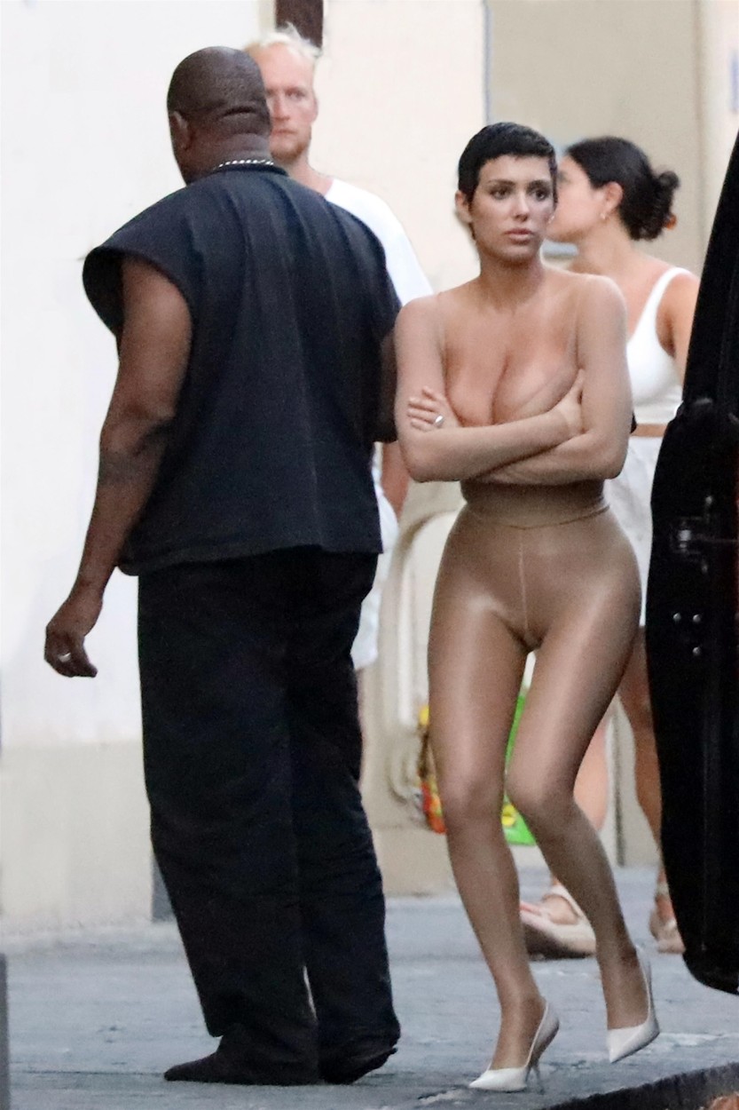 Kanye West într-o ținută neagră alături de Bianca Censori, care se acoperă cu o pernă mov, surprinși pe străzile din Italia