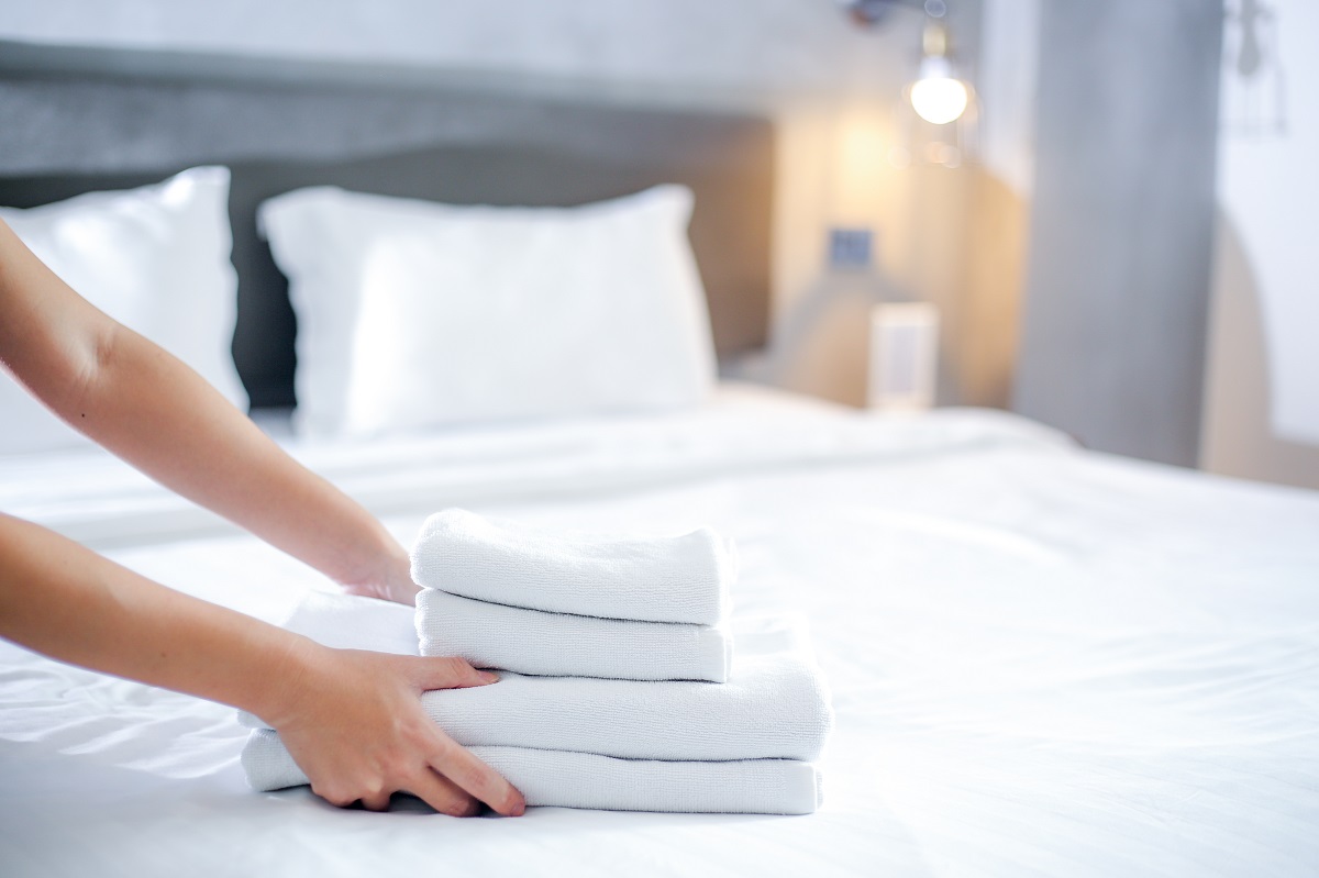 Două mâini care aranjează lenjeria de pat proaspăt spălată