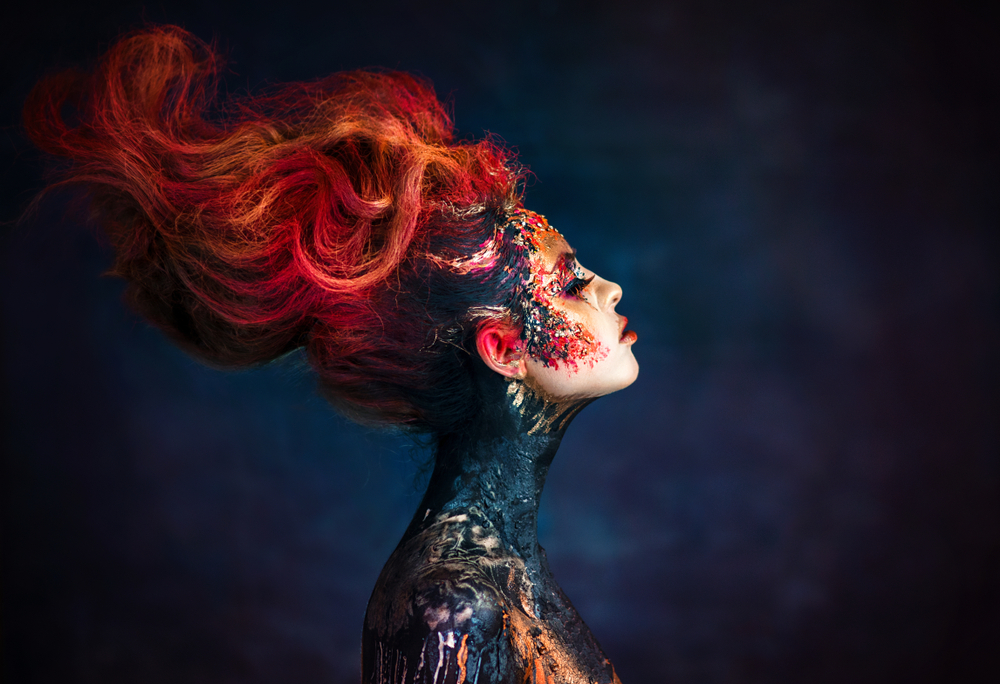 Fată frumoasă pictată pe față cu părul roșcat ridicat privește într-o parte