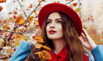 O femeie frumoasă care paortă o pălărie roșie și își pune în evidență culoarea de păr la modă în toamna anului 2023