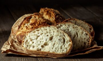 O pâine care stă pe o masă și este feliată pentru a ilustra cum să mânânci pâine fără să te îngrași