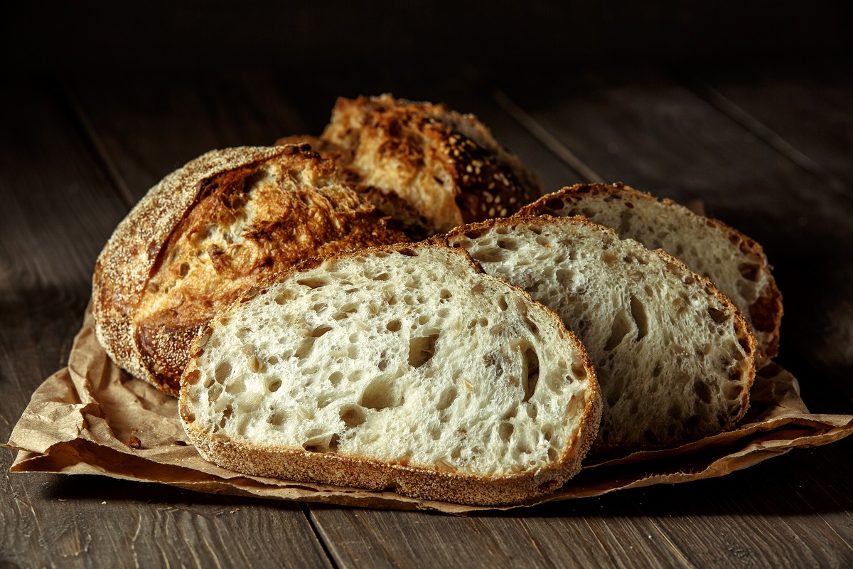 O pâine care stă pe o masă și este feliată pentru a ilustra cum să mânânci pâine fără să te îngrași
