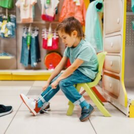 Un copil care probează o pereche de încălțări într-u magazin