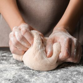 Două mâini de femeie care frământă un altau de pâine
