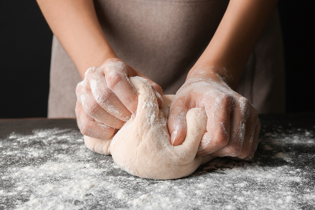 Două mâini de femeie care frământă un altau de pâine