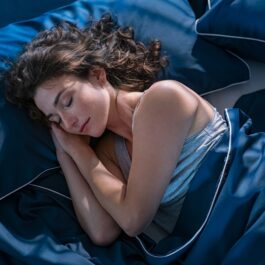 O femeie frumoasă care doarme într-un pat pentru a ilsutra metoda prin care poți să adormi în mai puțin de două minute