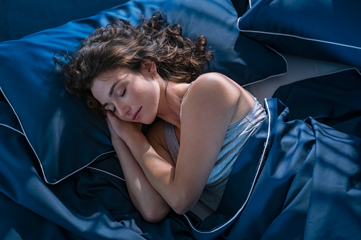 O femeie frumoasă care doarme într-un pat pentru a ilsutra metoda prin care poți să adormi în mai puțin de două minute