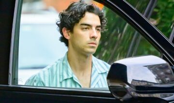 Joe Jonas, la mașină, fotografiat prin portieră, într-o cămașă deschisă la culoare