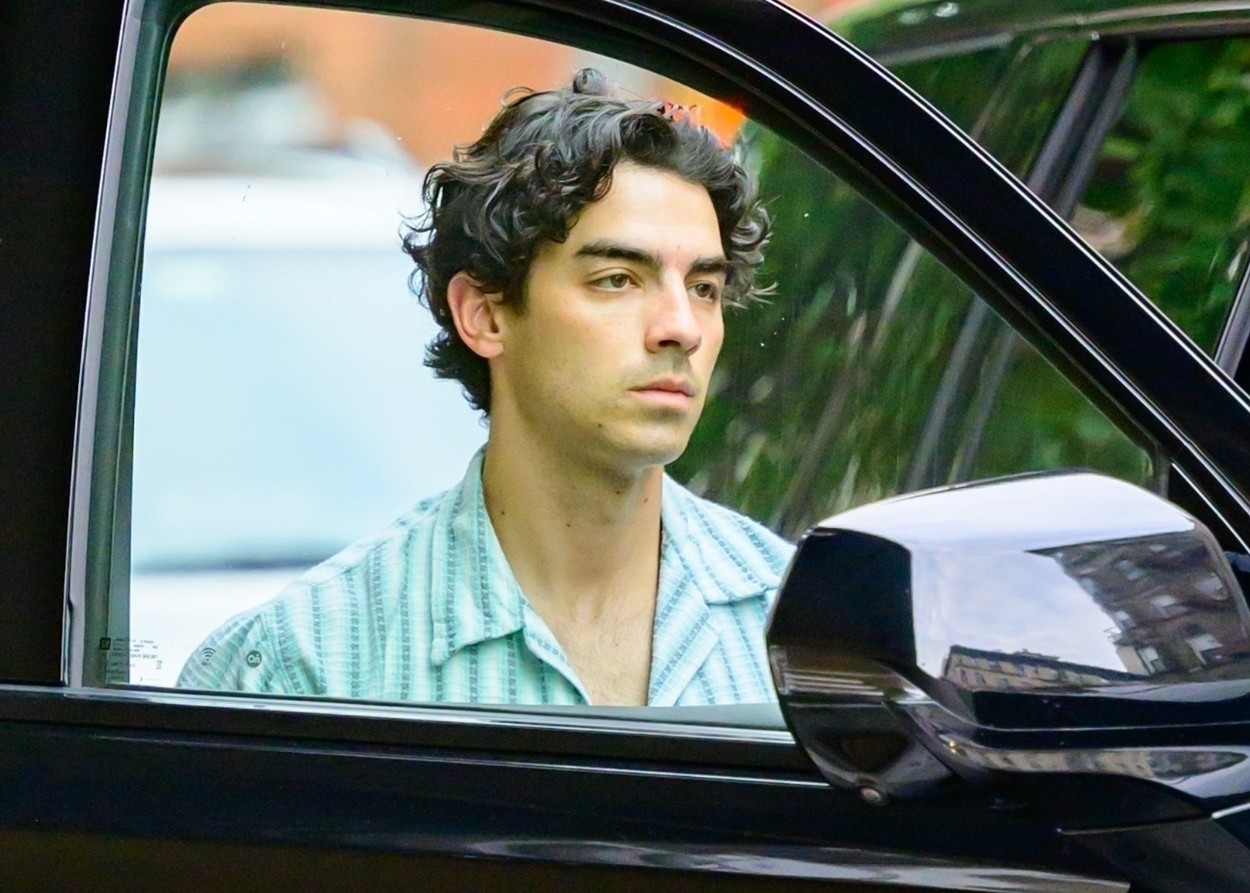 Joe Jonas, la mașină, fotografiat prin portieră, într-o cămașă deschisă la culoare