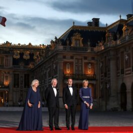 Regele și Regina Marii Britanii și Președintele Franței cu soția sa, îmbrăcați elegant, în fața Palatului Versailles