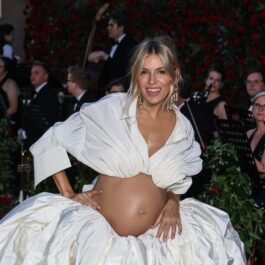 Sienna Miller, într-o rochie albă, cu burtica de gravidă la vedere, la un eveniment dedicat modei