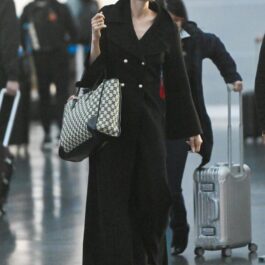 Angelina Jolie, într-un trenci negru, cu o geantă mare, de brand, în aeroport