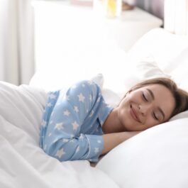 O femeie frumoasă care doarme într-un pat și se odihnește în timp ce ilustrează câte ore de somn sunt necesare pentru un organism sănătos