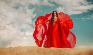 Fată frumoasă îmbrăcată într-o rochie roșie stă în deșert