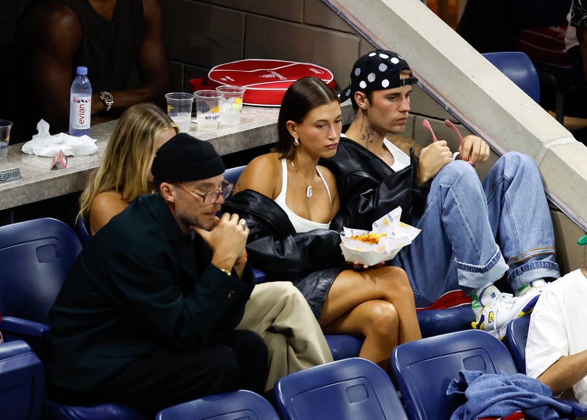 Hailey Bieber într-un top alb și o geacă din piele, atlărui de soțul său care poartă o ținută asemănătoare