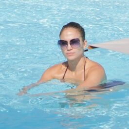 Jennifer Lopez în timp ce poartă costum de baie și înoată într-o piscină
