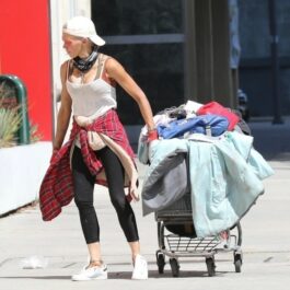 Loni Willison, pe stradă, îmbrăcată sărăcăcios, trage un căruț cu haine după ea