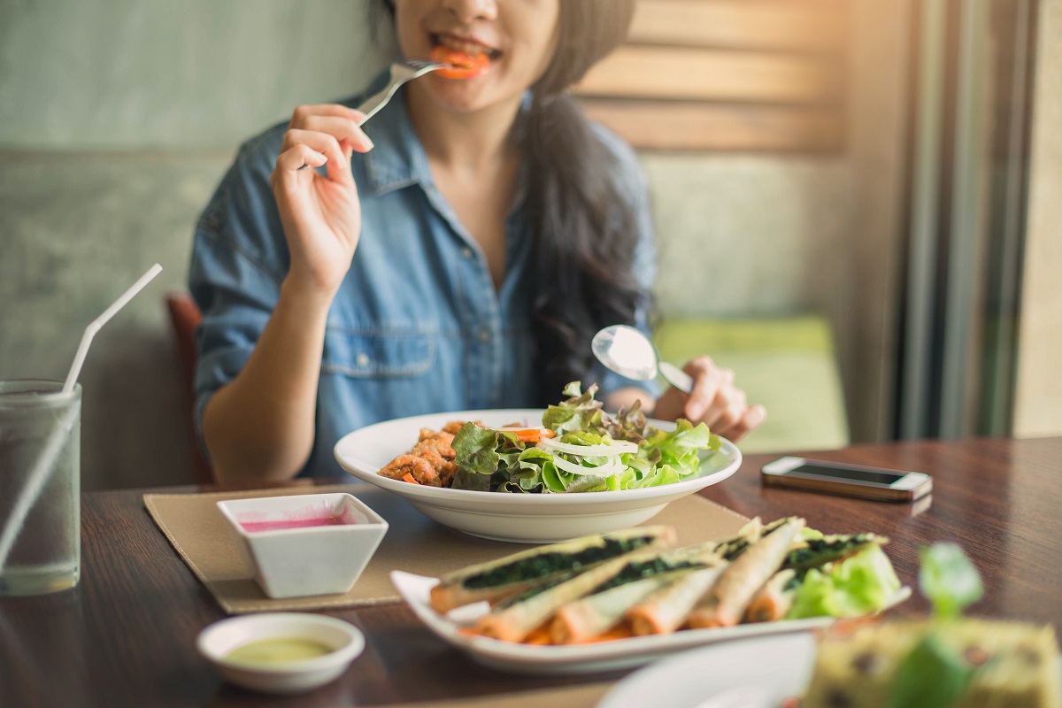 O femeie care stă la masă și mănâncă pentru a ilustra motivul pentru care ți se face foame des
