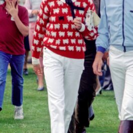 Prințesa Diana, la un joc de polo, într-un pulover roșu cu oi albe și o oaie neagră și blugi albi